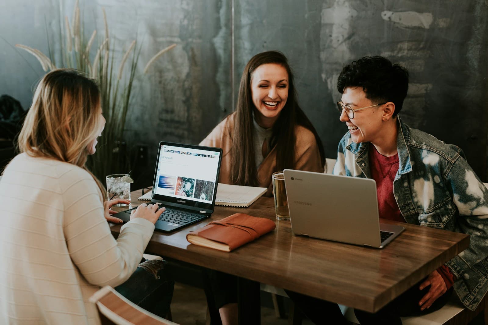 Jeune équipe souriante collaborant autour d'un ordinateur portable dans un bureau lumineux